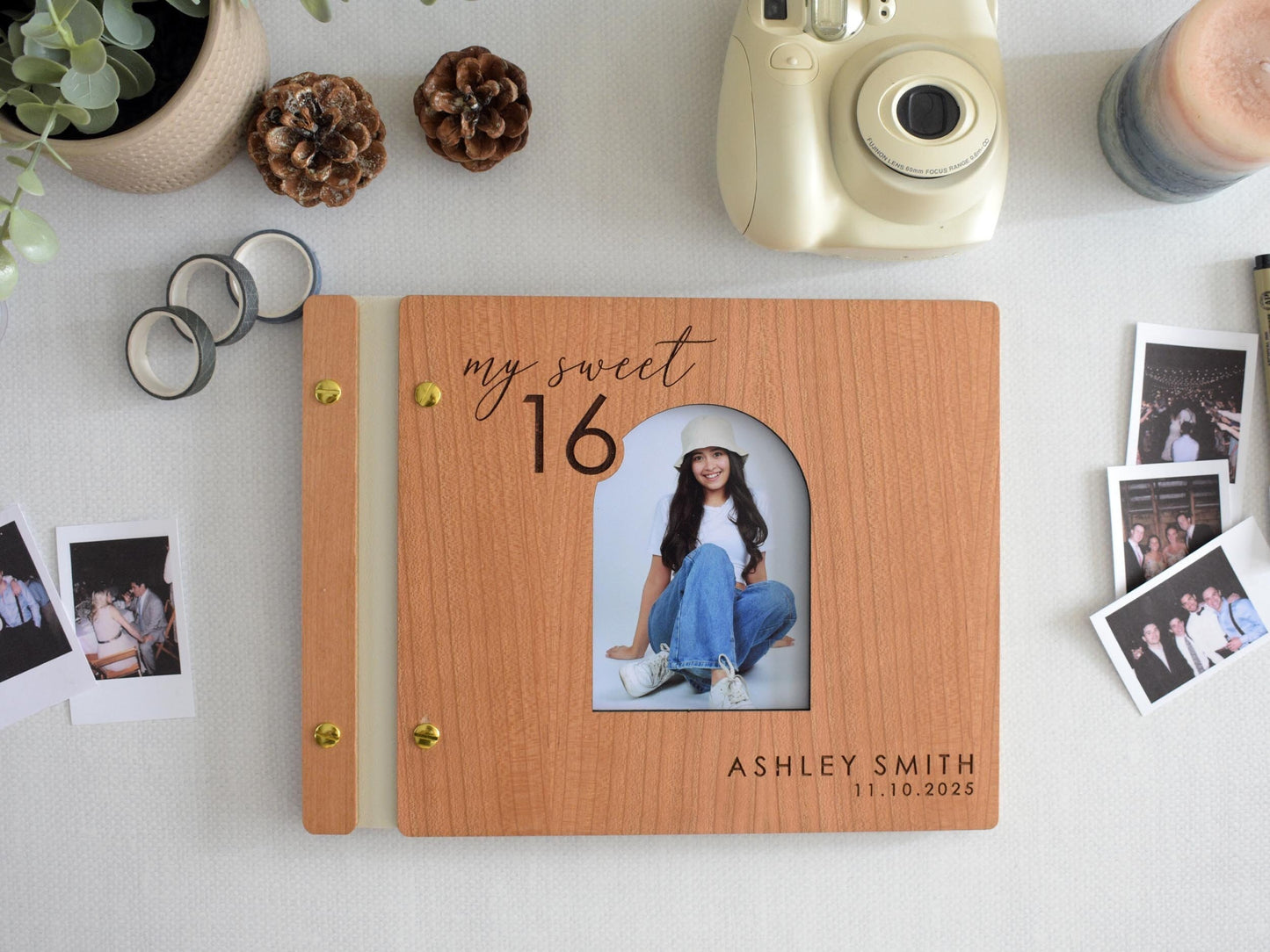 Custom wooden Sweet 16 guest book with a personalized photo and name engraving. Features a cherry wood cover, gold screws, and my sweet 16 design. Ideal for capturing special memories and messages. Surrounded by Polaroid photos and stationery.