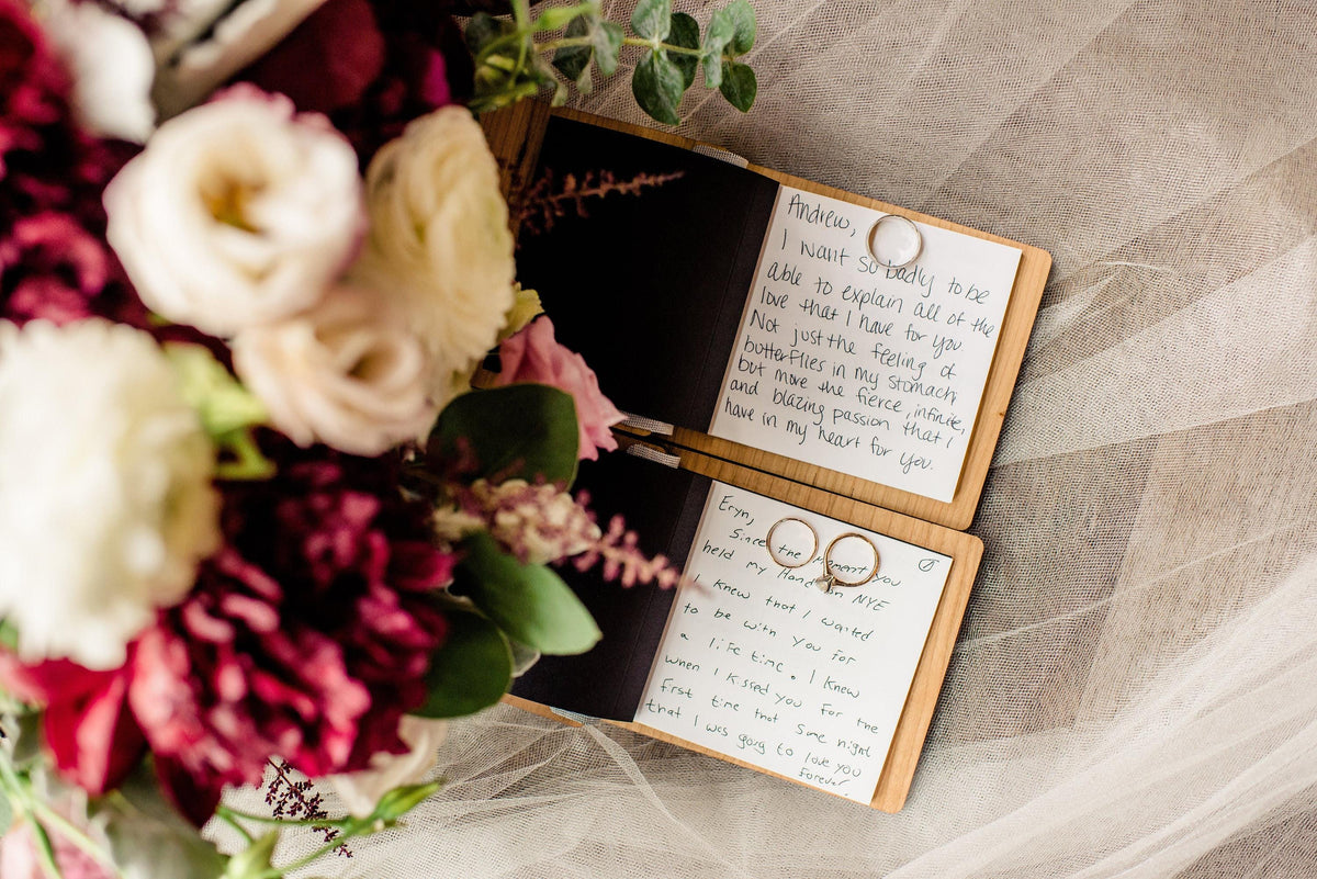 a bouquet of flowers and two open notebooks with handwritten messages, placed on a white surface.