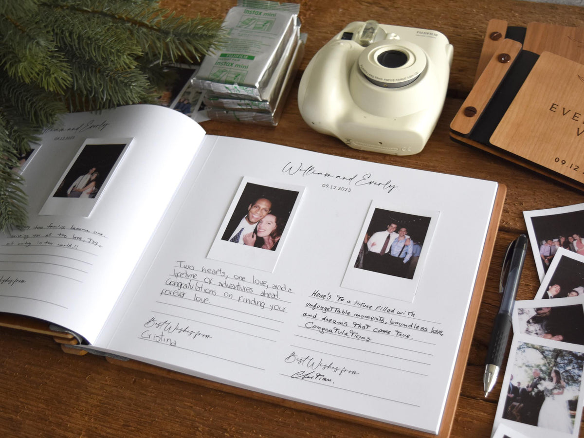 a wedding guest book with handwritten notes, a white Polaroid camera, and some photographs on a wooden surface.