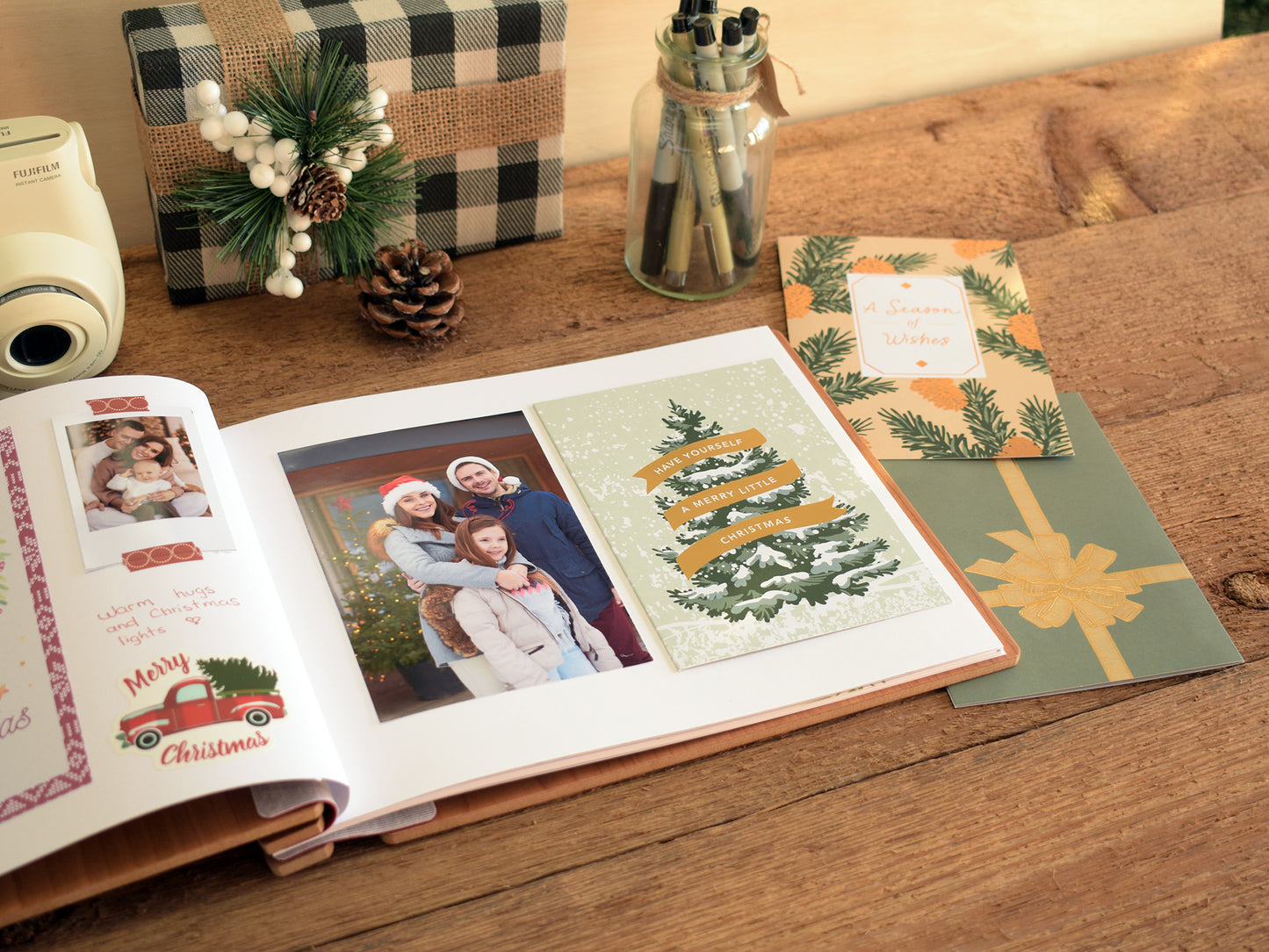 a family photo album with a couple of photographs, a Christmas card, and a gift box on a wooden table.