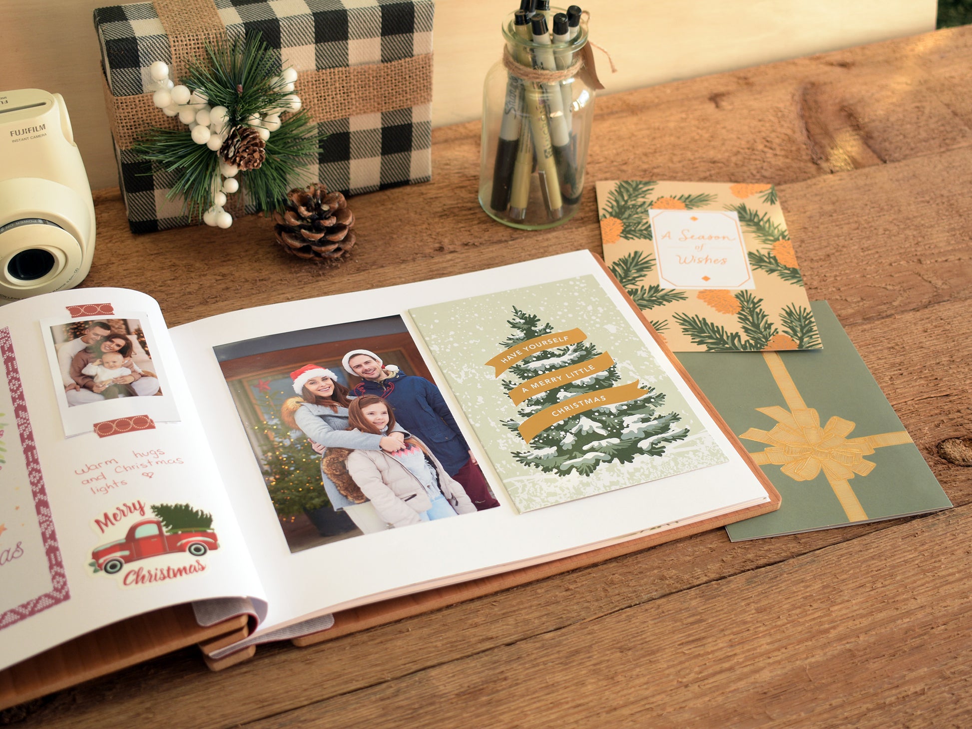 a family photo album with a couple of photographs, a Christmas card, and a gift box on a wooden table.