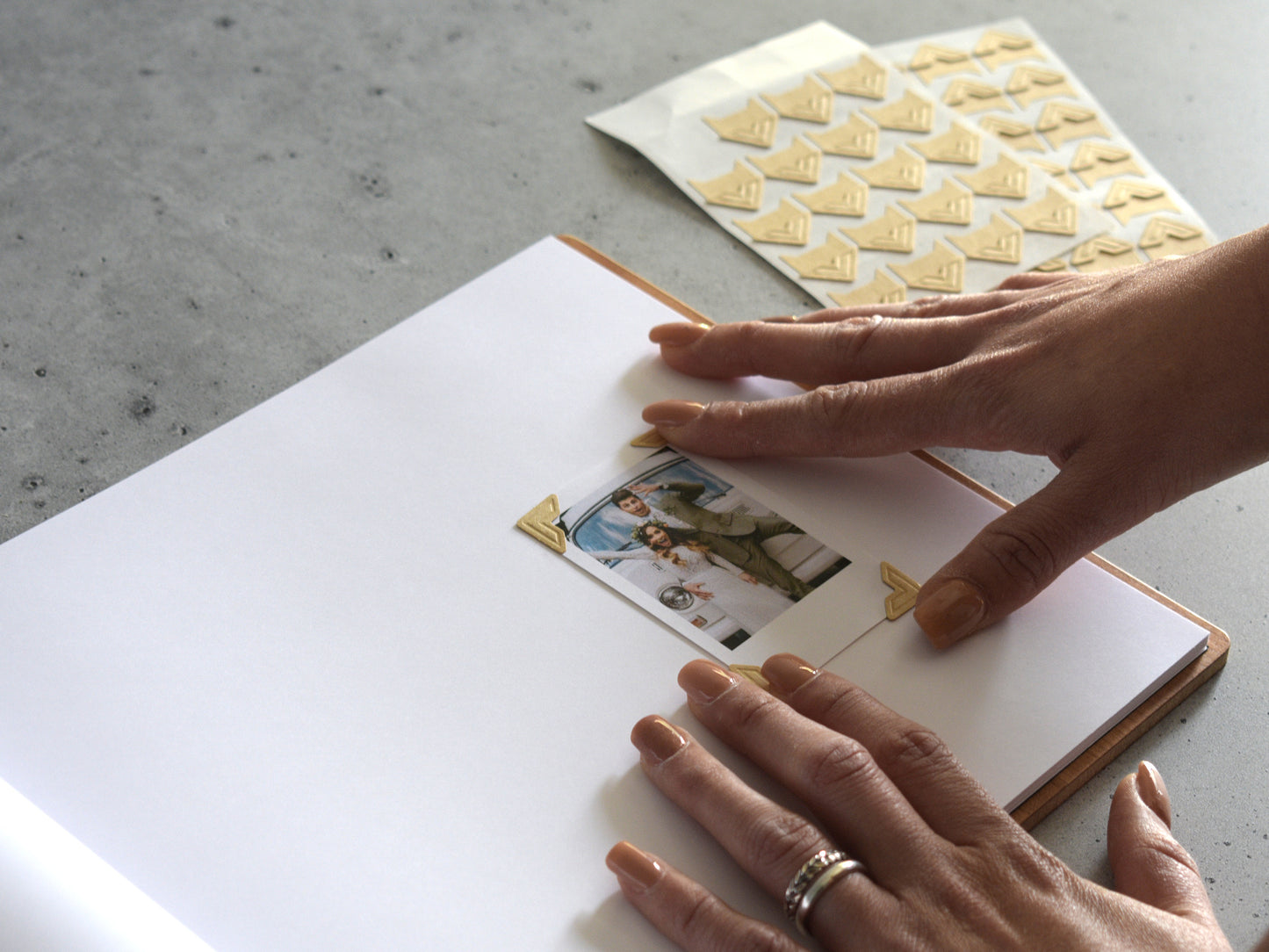 A person's hands are placing a photo into a photo album, with a patterned paper on the side.