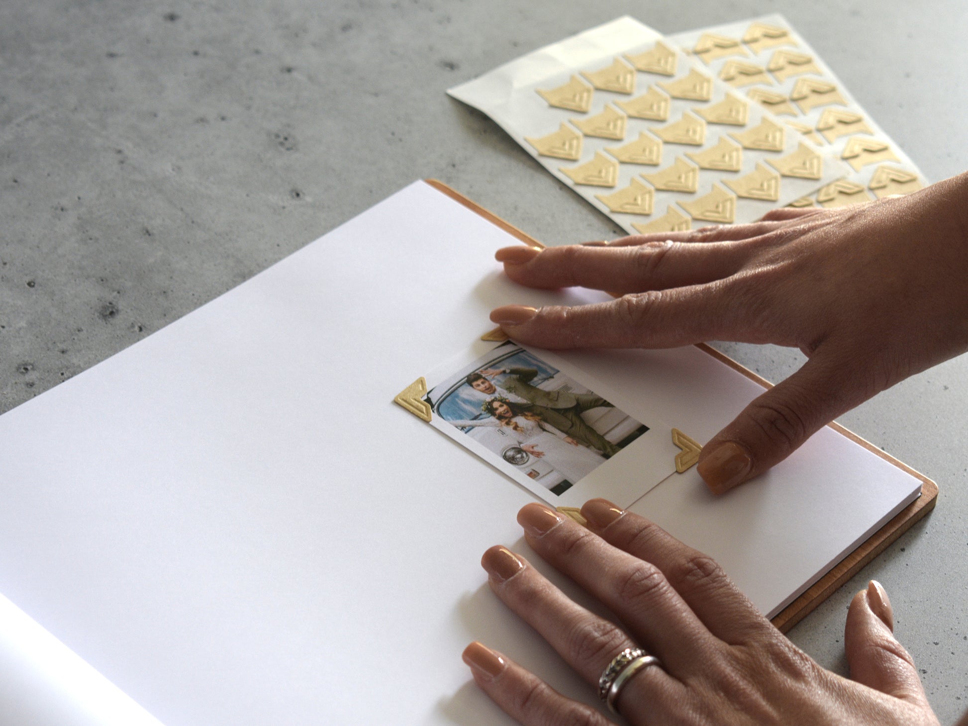 A person's hands are placing a photo into a photo album, with a patterned paper on the side.
