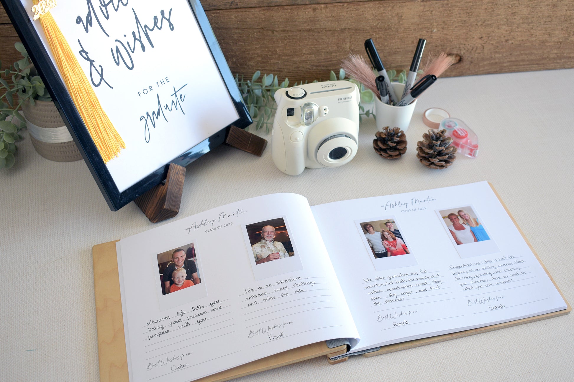 a graduation-themed display with a framed sign, a camera, and a notebook with photos and handwritten notes.