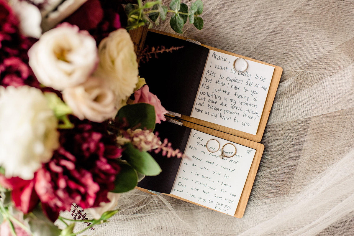 a bouquet of flowers and two open notebooks with handwritten messages, placed on a white surface.