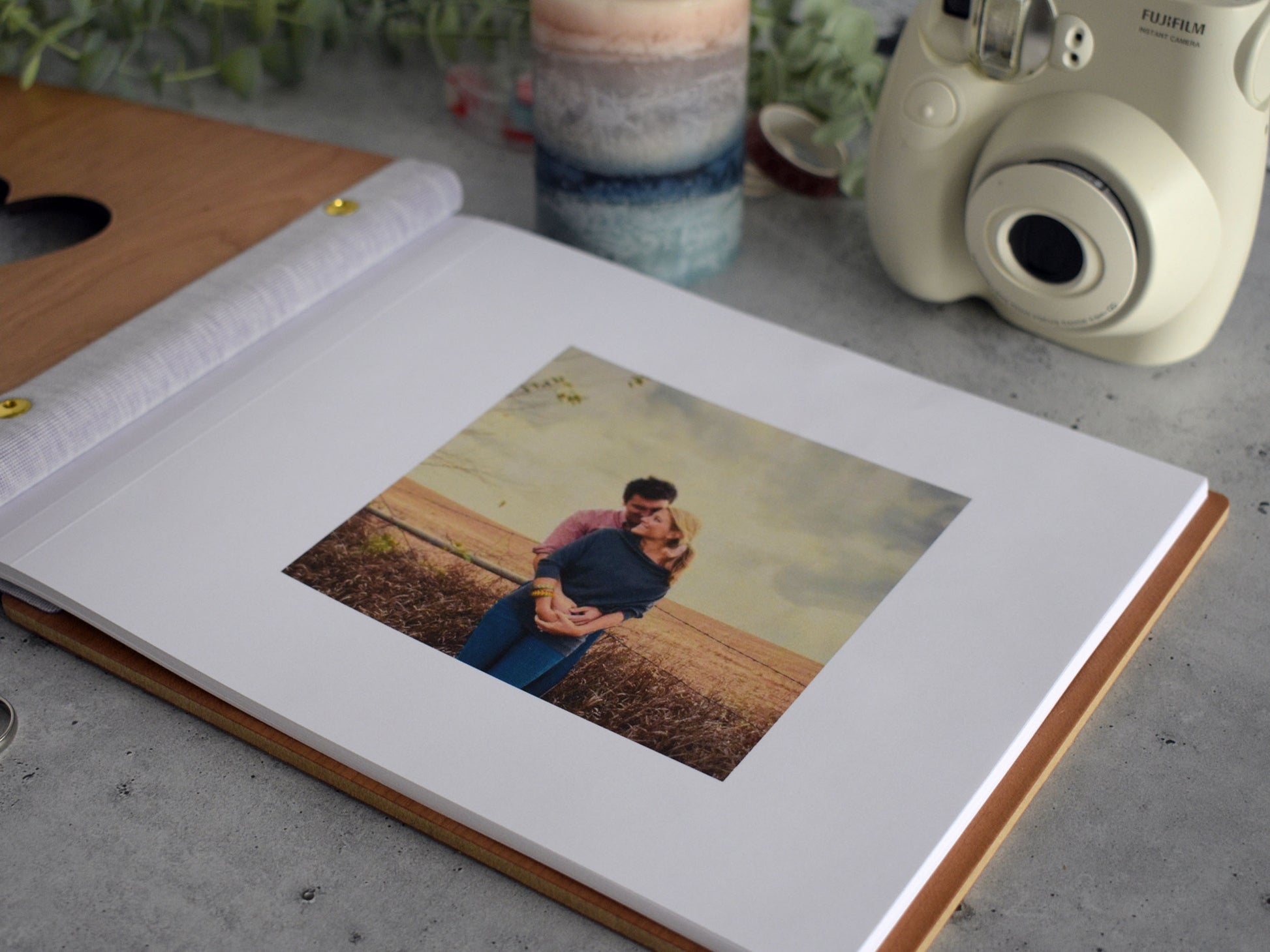 a close-up of a photo album with a printed photograph of a couple embracing in a field, placed on a wooden surface.