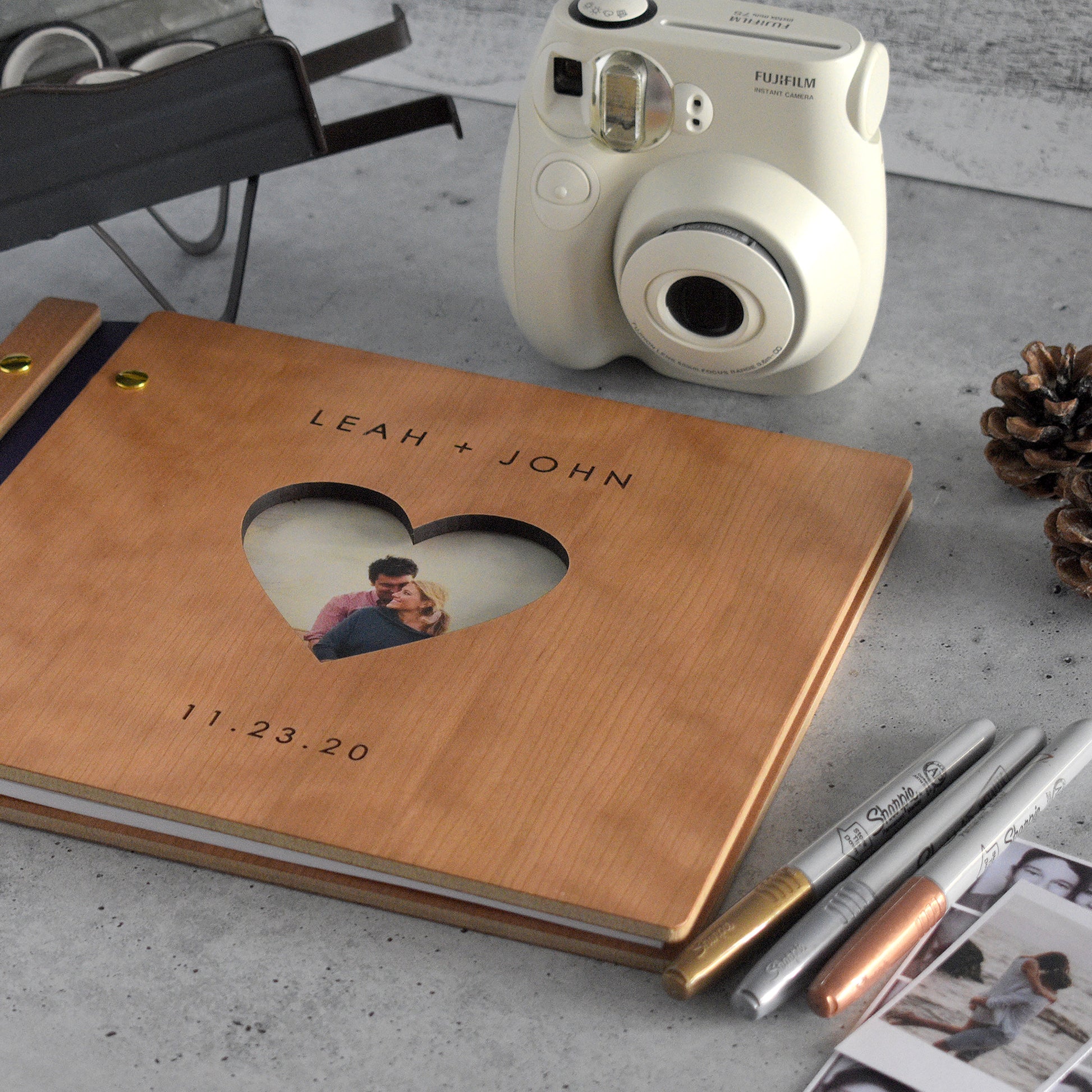 An 8.5x11" guest book lies on a table. Made of cherry wood, purple vegan leather binding, and gold hardware. The front cover reads “Leah + John, 11.23.20"