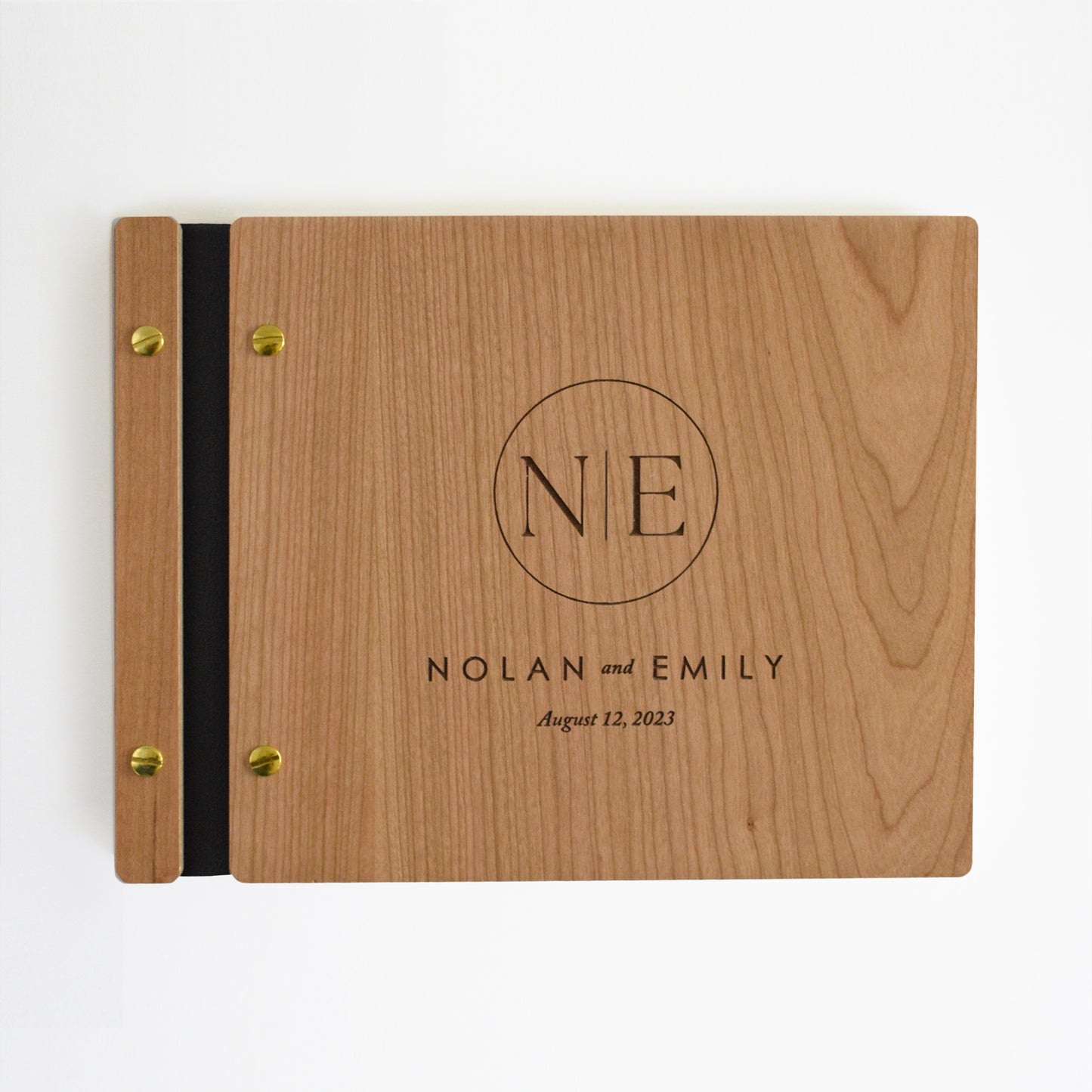Wedding guest book made out of cherry wood, black vegan leather, gold hardware, and monogram design for the engraving.