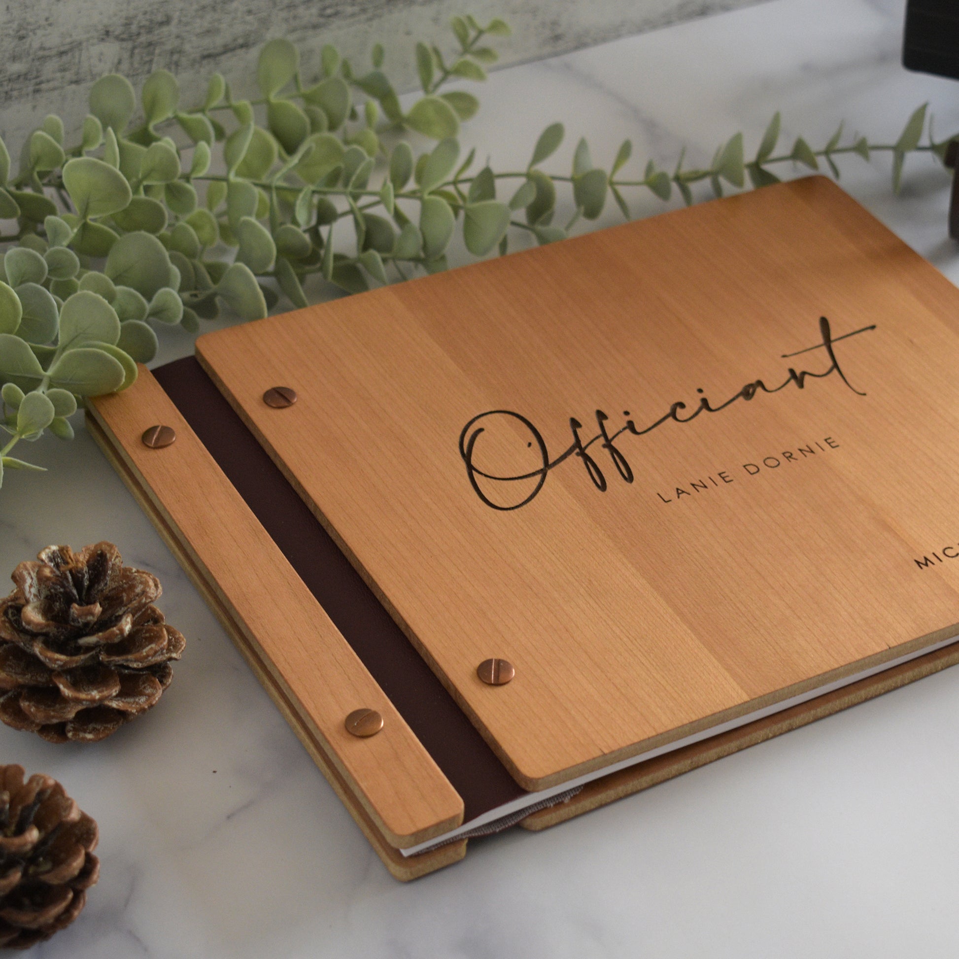 8.5x11" sized book made out of cherry wood, copper hardware, and black vegan leather. This is the perfect gift for your officiant on your wedding day.