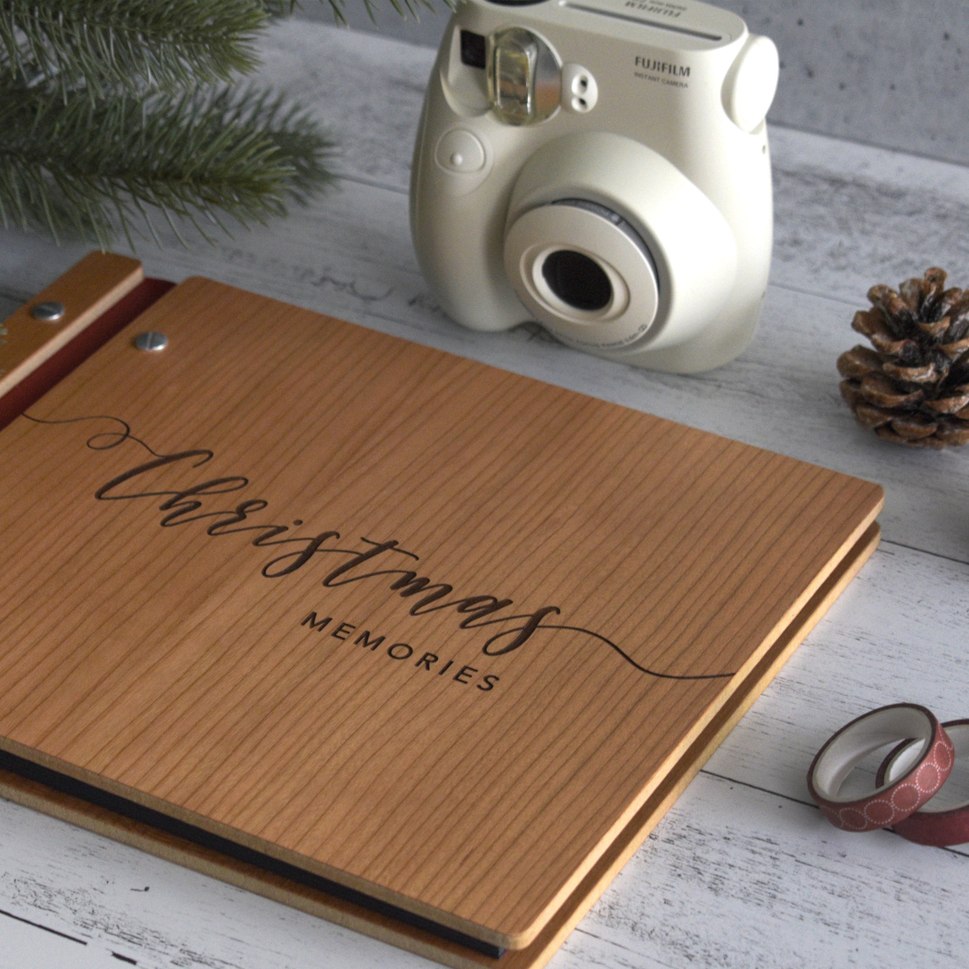 An 8.5x11" guest book lies on a table. Made of cherry wood, burgundy vegan leather binding, and silver hardware. The front cover reads Christmas Memories.